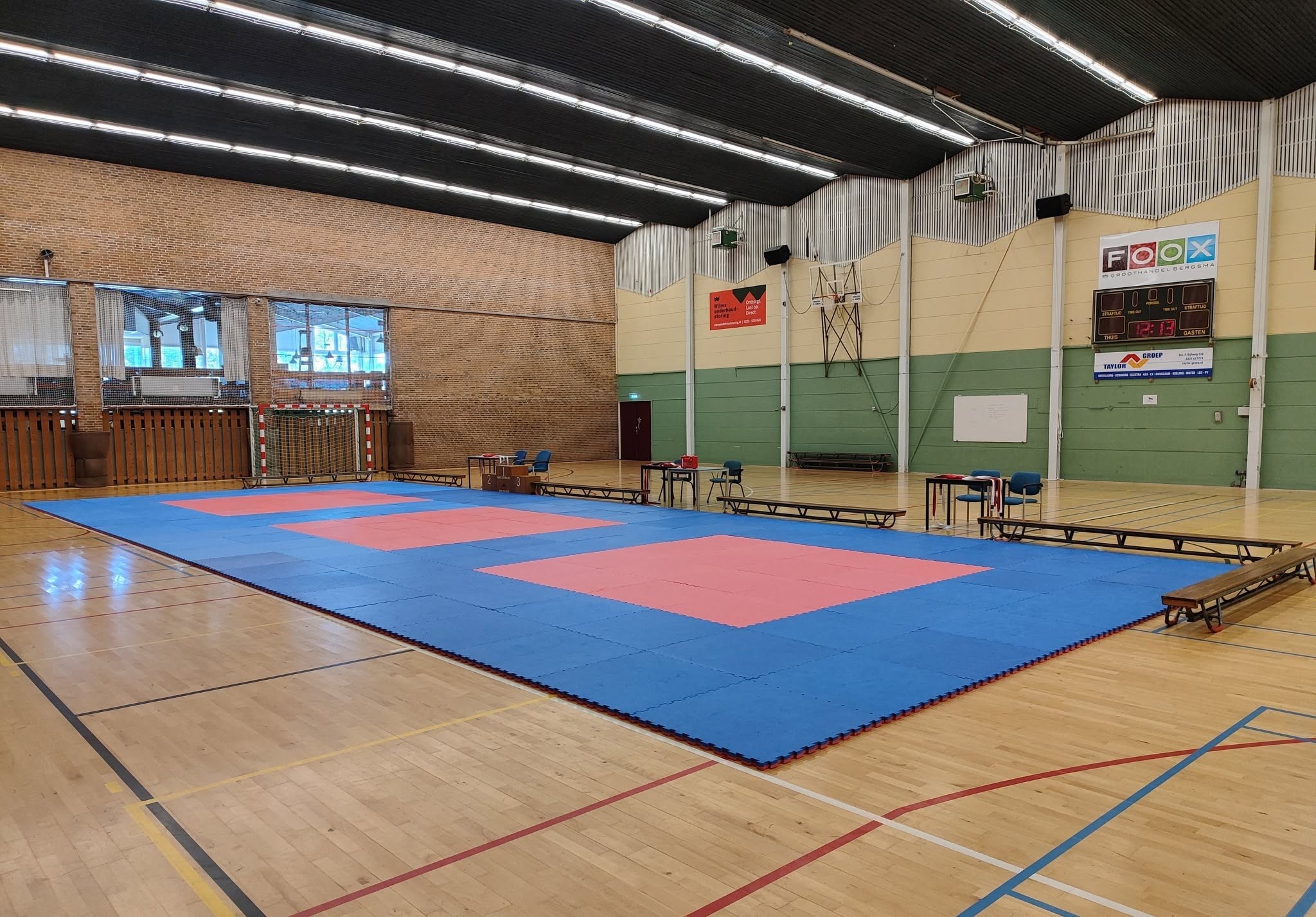 Sporthal met drie judowedstrijdmatten en jurytafels